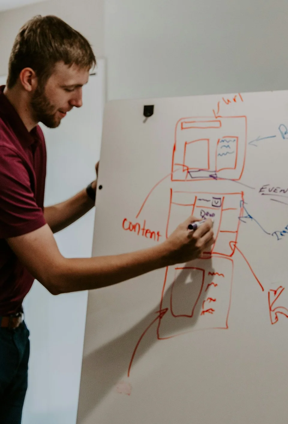 Developer sketching an app wireframe on a whiteboard with a colleague