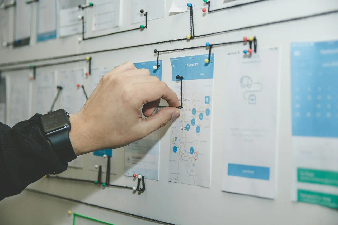 A hand mapping a workflow on a wall of connected process cards